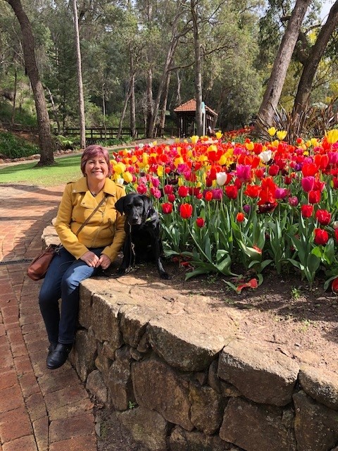 Picture of Colleen with her dog Rhian in front of tulips.