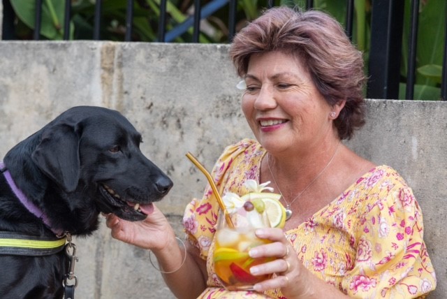 Picture of colleen with a cocktail in her hand and her guide dog by her side.