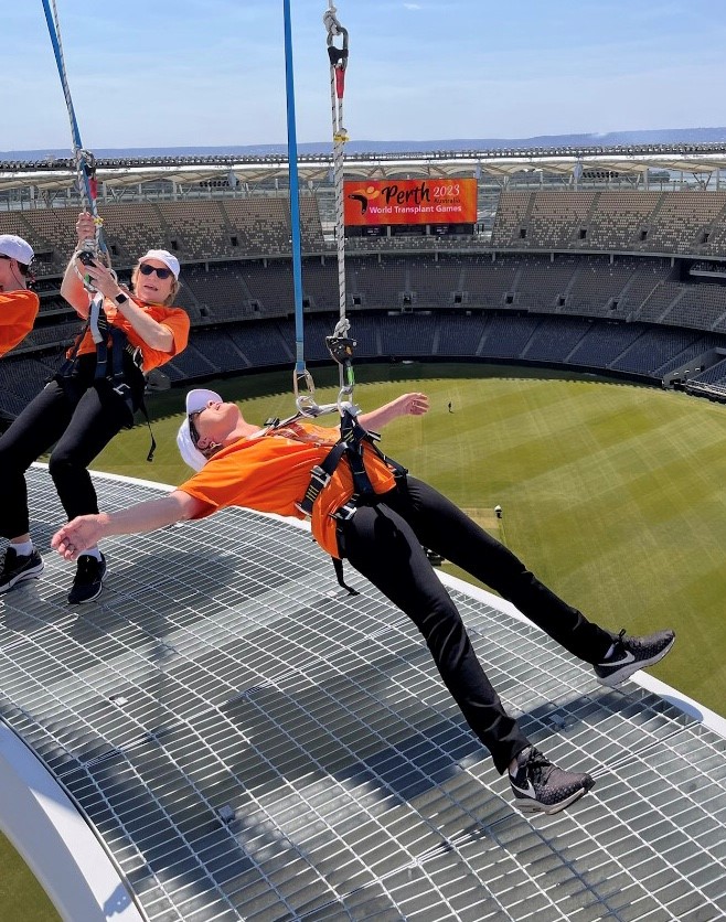 Picture of Colleen hanging in harness totally off the platform with arms and legs spread hanging in balance.