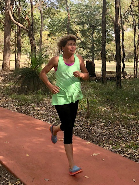 Picture of Calleen in full running gear powrering down a country lane in the summer.